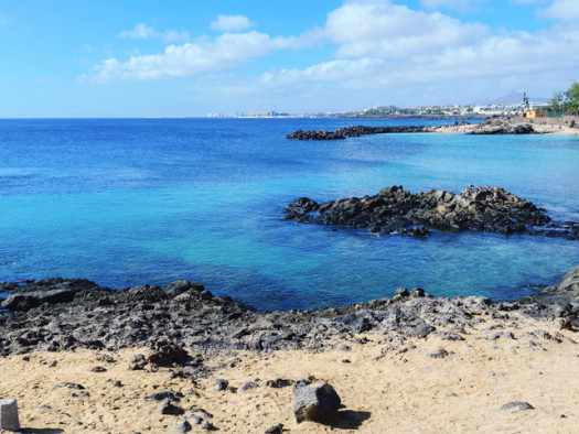 Lagoon with turquoise clear water in Playa Jablillo beach, in Costa Teguise, Lanzarote, Canary islands. Sandy beach with blue sea, volcanic rocks